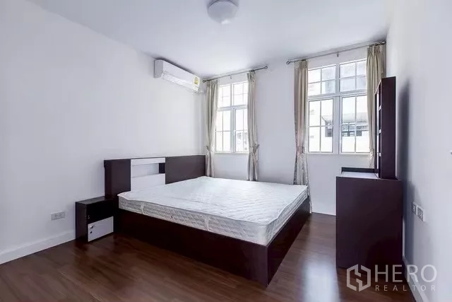 Townhouse for rent in Watthana, Bangkok - Second bedroom with bed, air conditioner and two large windows.