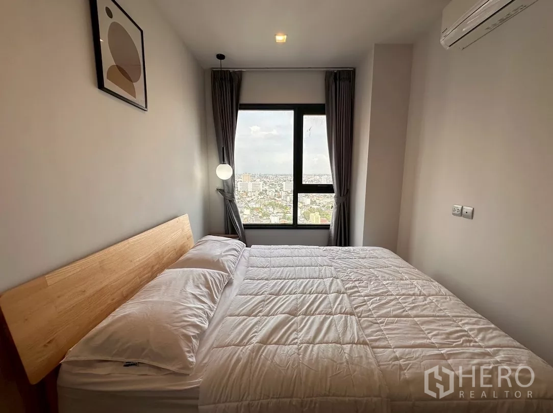 Condominium for rent in Chatuchak, Bangkok - Primary bedroom with city-facing window, gray curtains and queen bed.