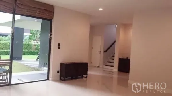 Detached House for rent in Bang Kapi, Bangkok - Bright ground-floor living area with sliding glass door to the patio, glossy floors and a staircase.