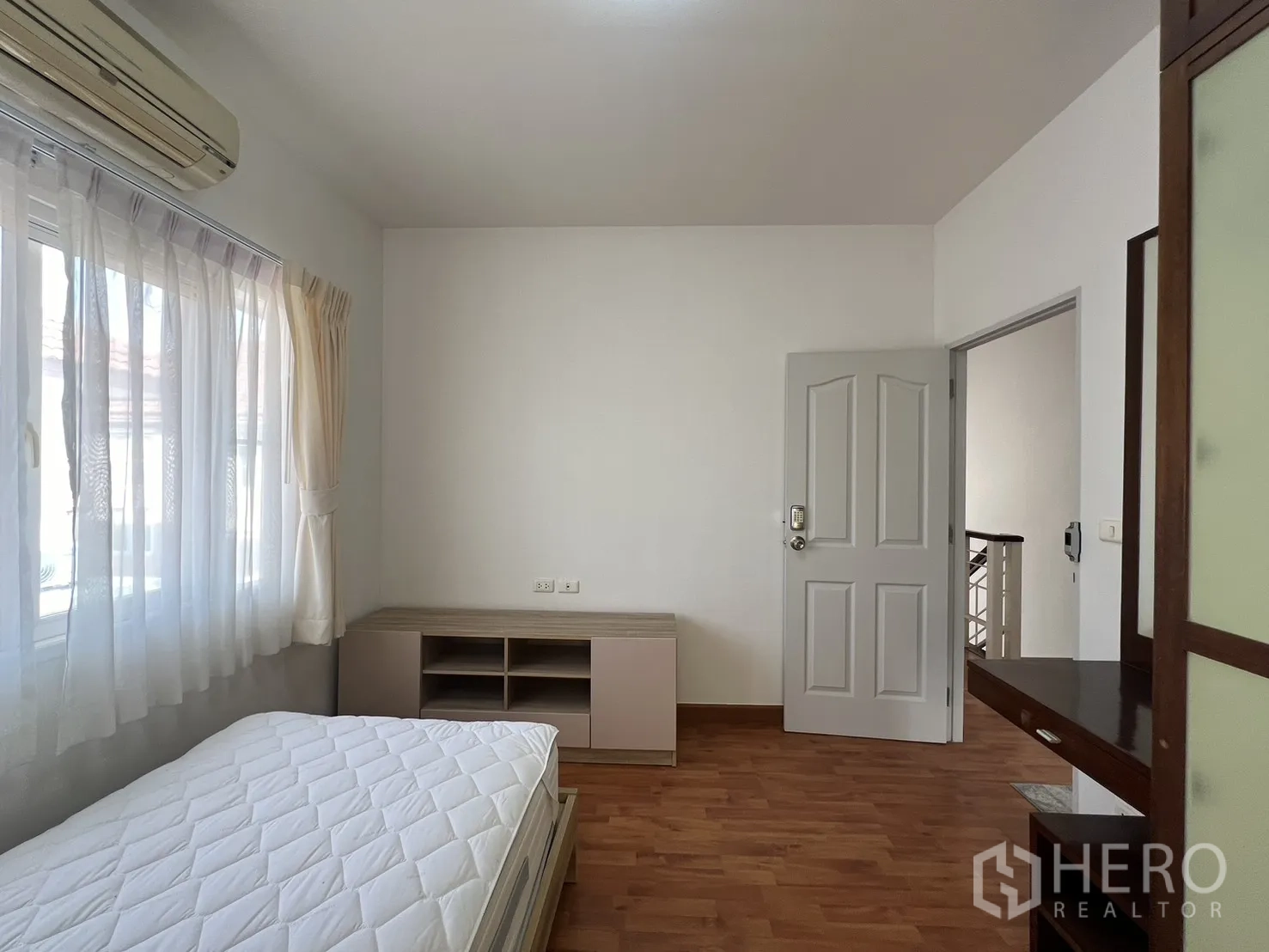 Detached House for rent in Bang Kapi, Bangkok - Bedroom with dark wood wardrobe and single bed beside corner windows.