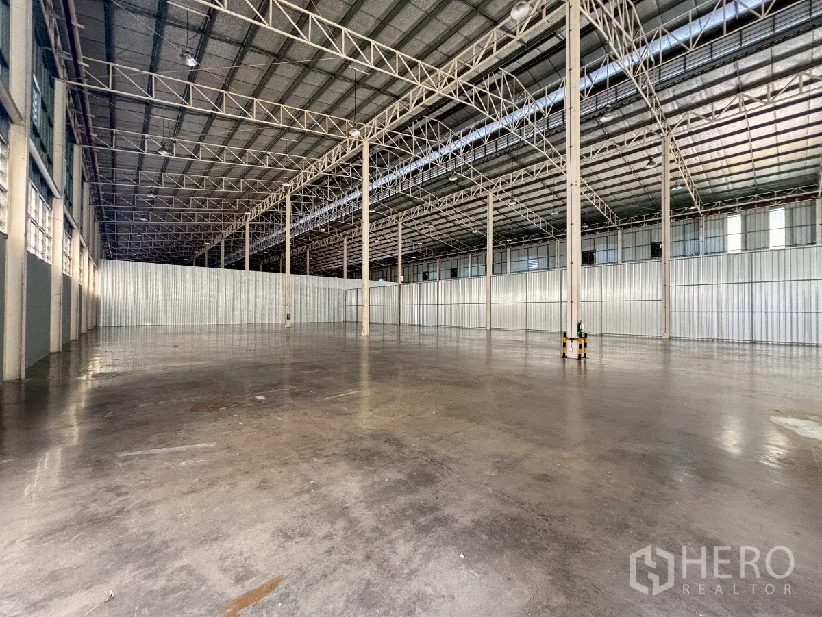 Warehouse for rent in Bang Sue, Bangkok - Open clear-span warehouse showing wide column grid, metal wall partitions and skylight strips.
