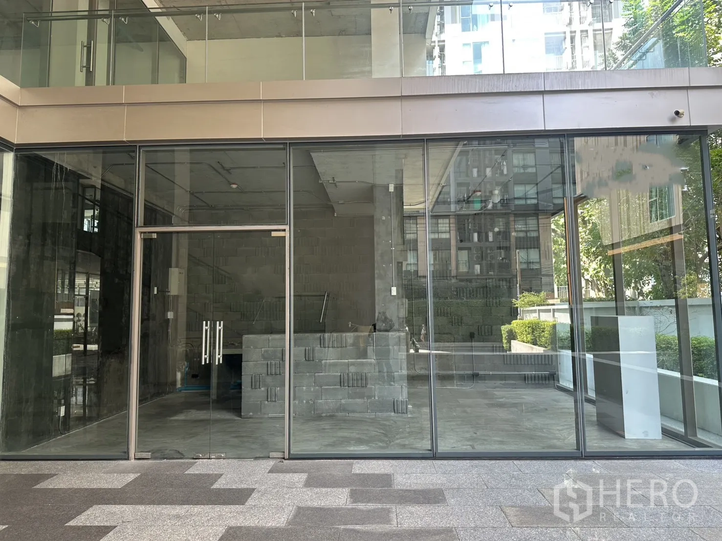 零售空间 出租在Phra Khanong, Bangkok - 外立面图，整面落地玻璃与双开门，一层现代建筑店铺。