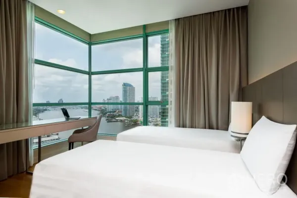 Condominium for rent in Bang Kho Laem, Bangkok - Corner bedroom with twin beds and panoramic Chao Phraya River views.