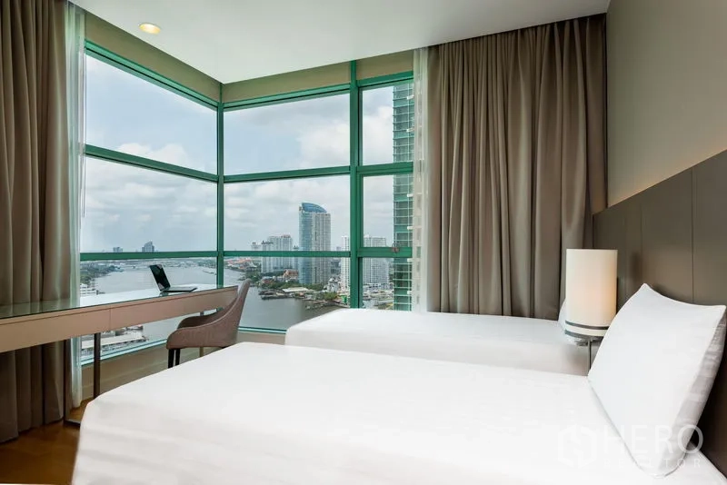 Condominium for rent in Bang Kho Laem, Bangkok - Corner bedroom with twin beds and panoramic Chao Phraya River views.