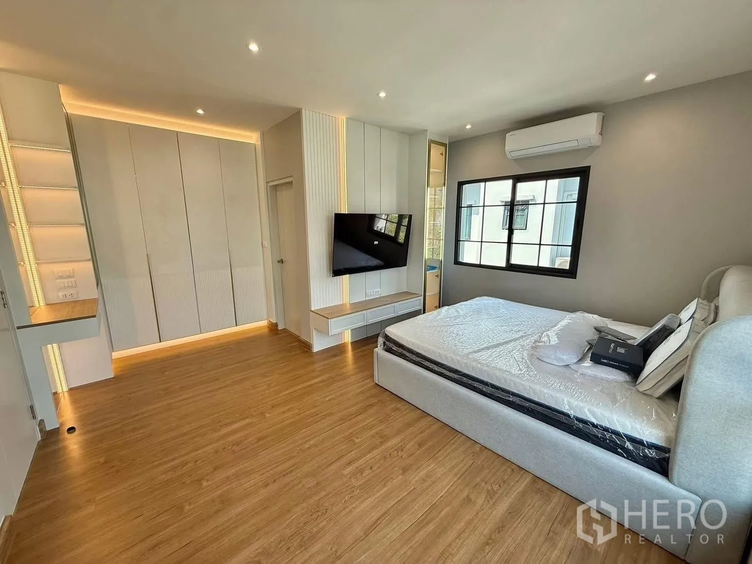 Detached House for rent in Bang Phli, Samut Prakan - Master bedroom with wood floors, built-in wardrobes, wall-mounted TV, large window and air conditioning.