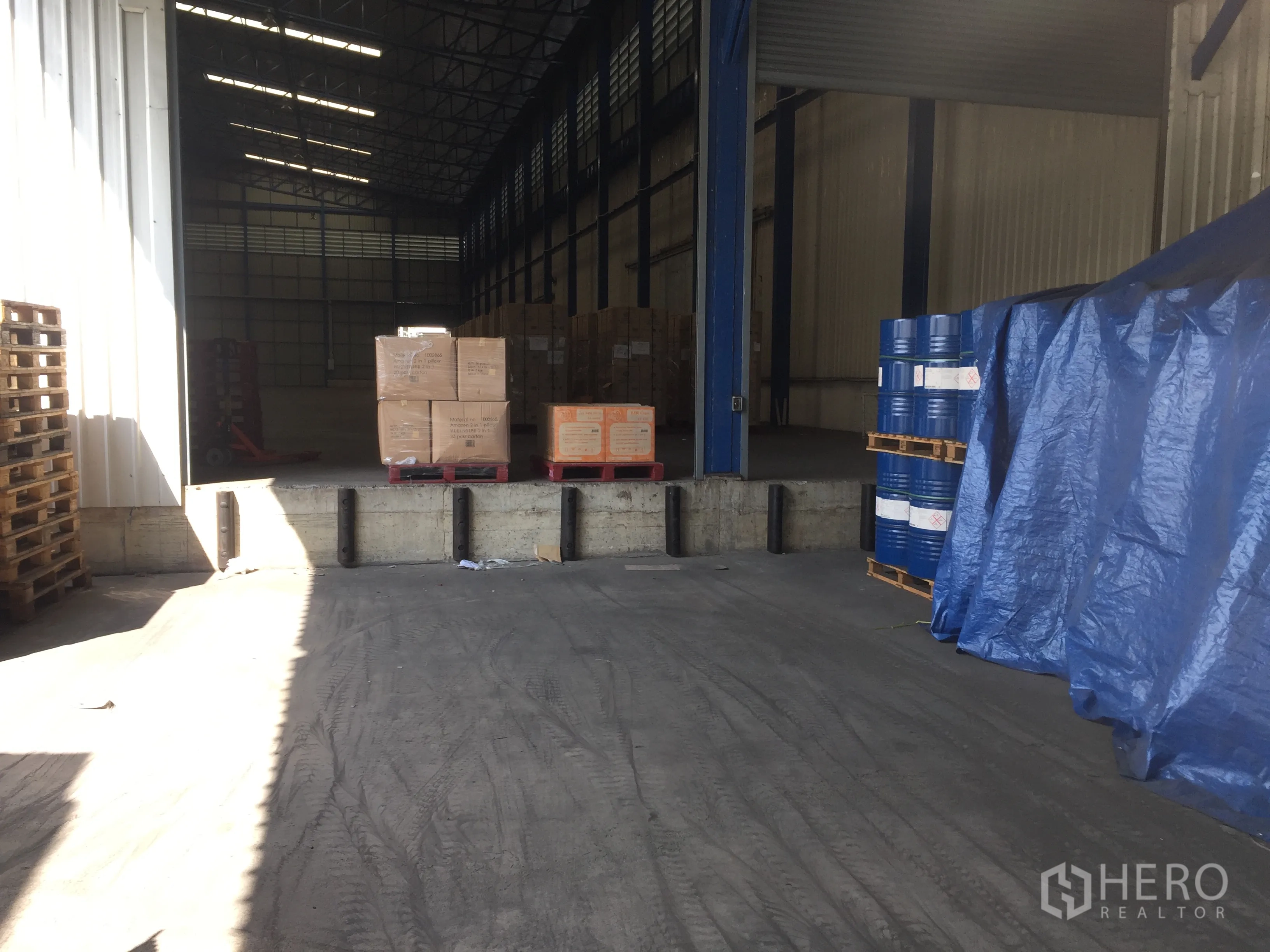 Warehouse for rent in Pak Kret, Nonthaburi - Dock area with boxes and drums on pallets leading into the warehouse interior.