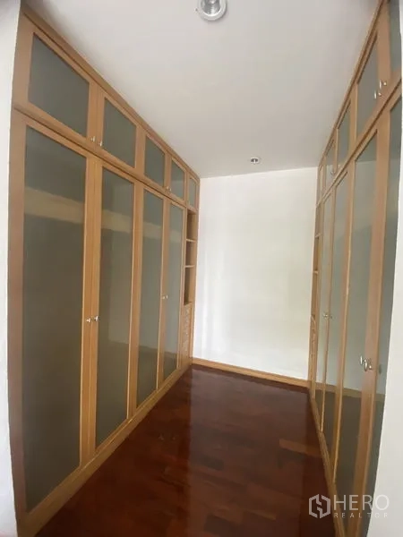 Condominium for rent - Walk-in wardrobe corridor with floor-to-ceiling built-in closets and polished wooden floor.