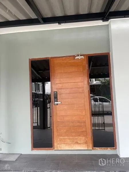 Townhouse for sale - Townhouse entrance with solid wooden door and side glass panels in Bang Phli