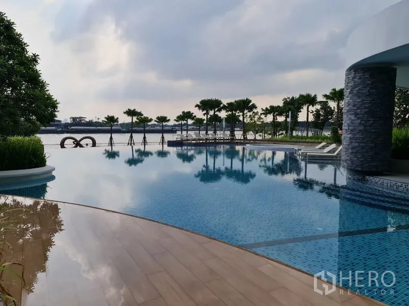 Condominium for sale in Yan Nawa, Bangkok - Riverside infinity swimming pool with sun loungers and palm landscaping at the condominium.