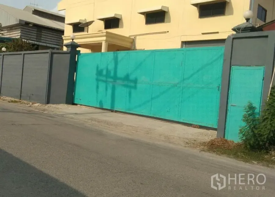 工厂 出租在Bang Phli, Samut Prakan - 工厂临街入口，高墙与宽大的绿色滑动大门。