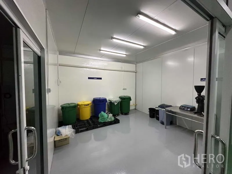 Factory for rent in Khlong Luang, Pathum Thani - Utility room with labeled bins, grinder and stainless workbench under bright lights.