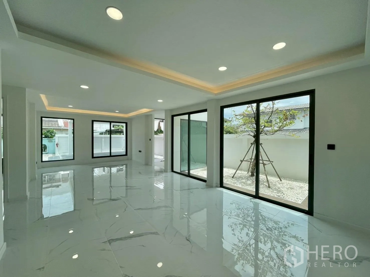 Detached House for sale in Chatuchak, Bangkok - Wide living room with recessed lighting and multiple windows facing the garden.