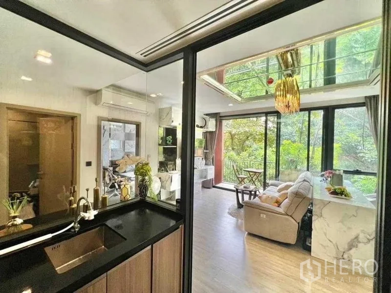 คอนโด ขายในWatthana, Bangkok - มุมมองจากครัวผ่านผนังกระจกไปยังห้องนั่งเล่นและระเบียงวิวสวน