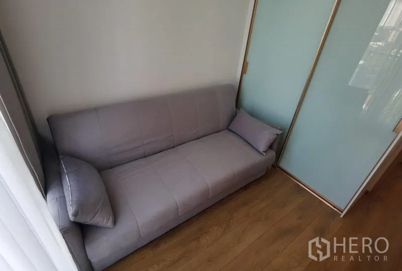 คอนโด ให้เช่าในWatthana, Bangkok - ห้องอเนกประสงค์ขนาดกะทัดรัด โซฟาสีเทา ข้างประตูกระจกฝ้าเลื่อน พื้นไม้