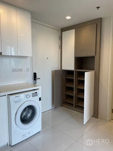 Condominium for rent in Sathon, Bangkok - Entryway with built‑in shoe storage cabinets beside the washing machine.