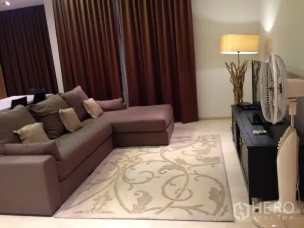 公寓 出售在Bang Rak, Bangkok - 客厅配L型沙发、落地窗帘、地毯与落地灯，氛围温馨。