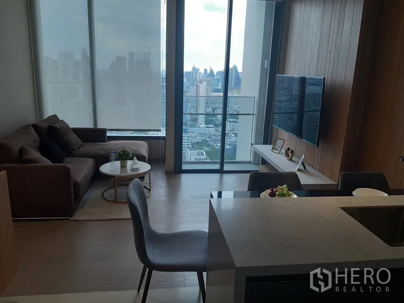 公寓 出租或出售在Watthana, Bangkok - 明亮客厅配沙发与电视墙，连通阳台，可眺望曼谷天际线。