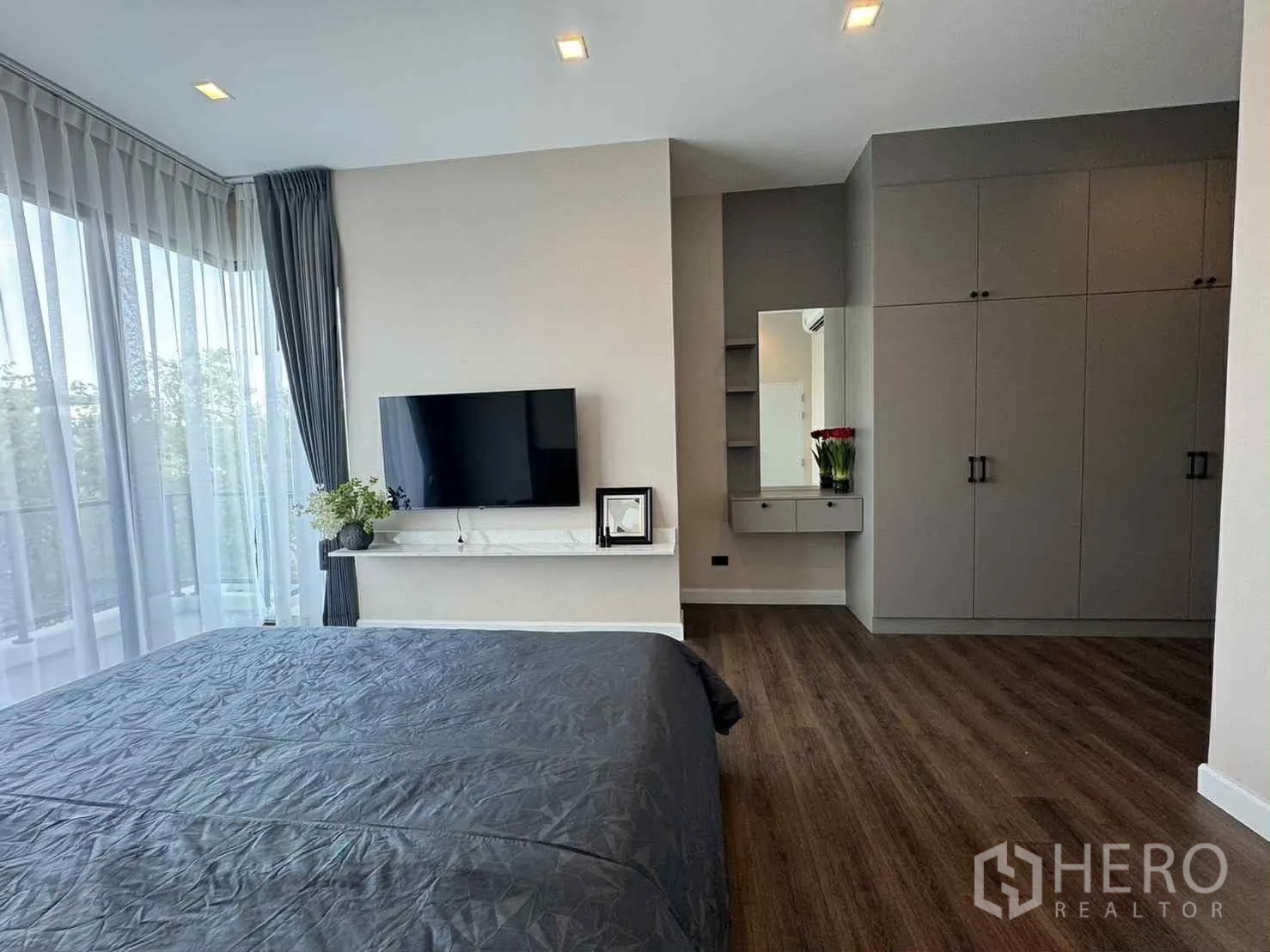 Detached House for rent in Bang Phli, Samut Prakan - Spacious bedroom with TV wall, wardrobes, vanity and corner windows with curtains.