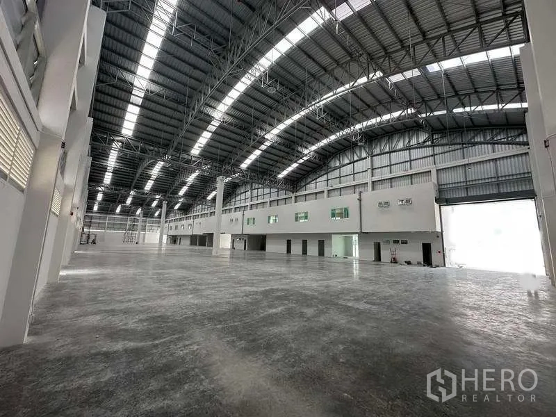 Factory for rent in Khlong Luang, Pathum Thani - High-bay warehouse with curved truss roof and skylights spanning a wide floor area.