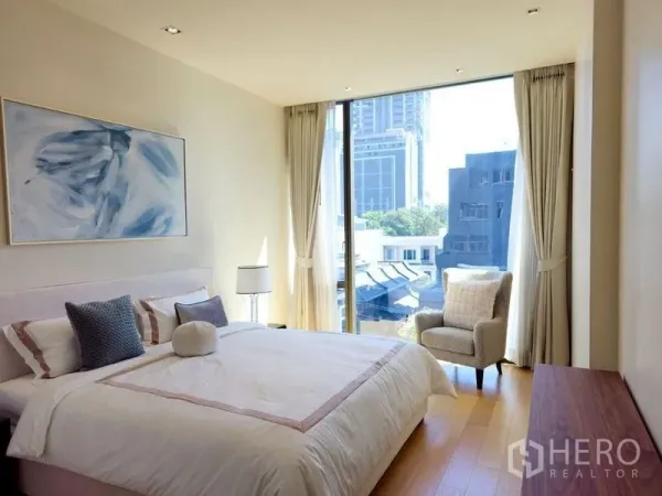 Condominium for rent or sale in Pathum Wan, Bangkok - Primary bedroom with large window, city view, king bed, and cozy armchair.