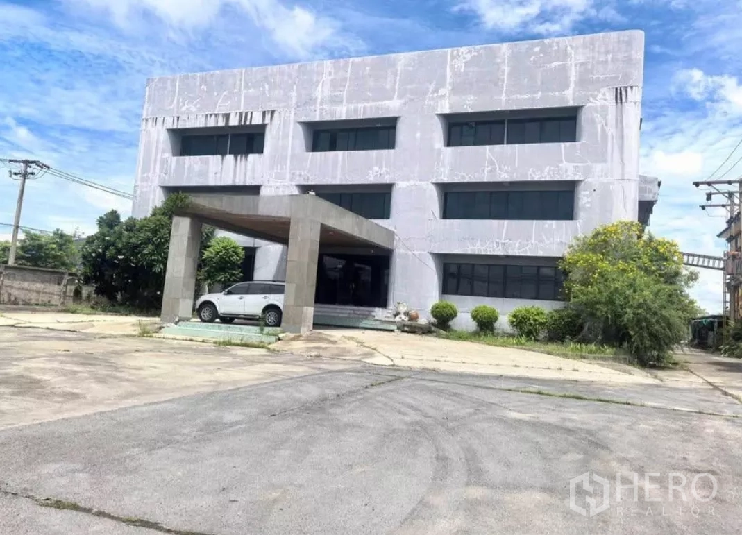工厂 出售在Bang Phli, Samut Prakan - 正面立面图：三层工业办公楼，门廊车道与绿化灌木