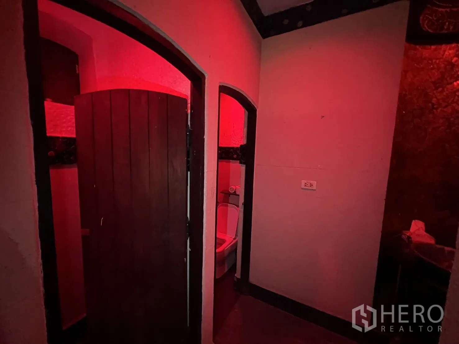 零售空间 出租在Watthana, Bangkok - 卫生间区域，拱形门与暖红色灯光。