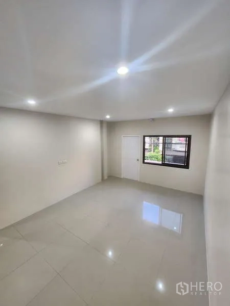 Townhouse for rent in Wang Thonglang, Bangkok - Second bedroom with neutral walls, window and ceiling lights.
