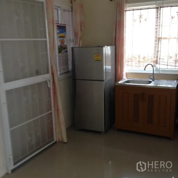 Detached House for rent in Suan Luang, Bangkok - Simple kitchen corner with stainless sink, wooden cabinet and silver refrigerator by windows