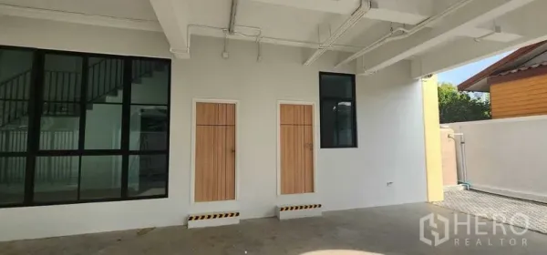 สำนักงานที่บ้าน ให้เช่าในBang Kapi, Bangkok - พื้นที่จอดรถชั้นล่างแบบมีหลังคา พร้อมประตูไม้สองบานและหน้าต่างกรอบดำ.