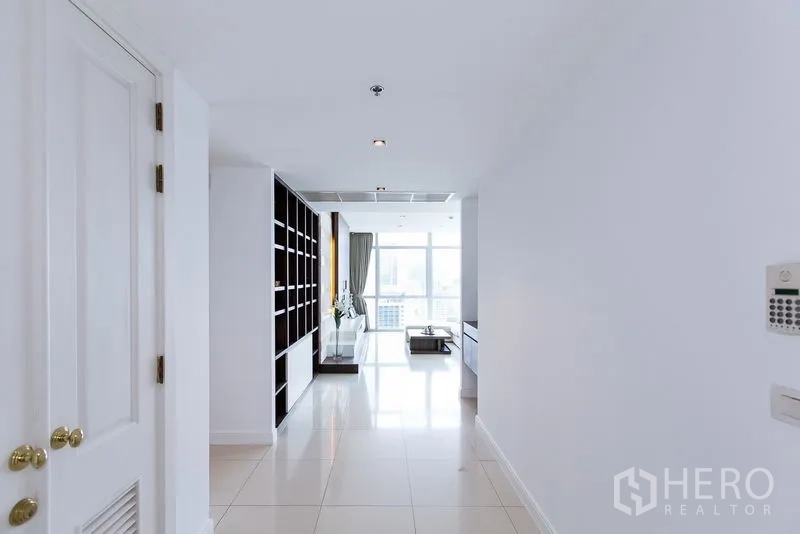 Condominium for rent in Pathum Wan, Bangkok - Entrance hallway leading to living room, showcasing tall shelving and natural light.