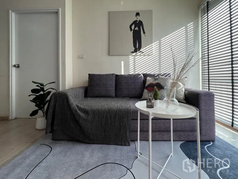 公寓 出租在Khlong Toei, Bangkok - 沙发角落特写，圆形小桌与玻璃摆件，阳光透过百叶窗