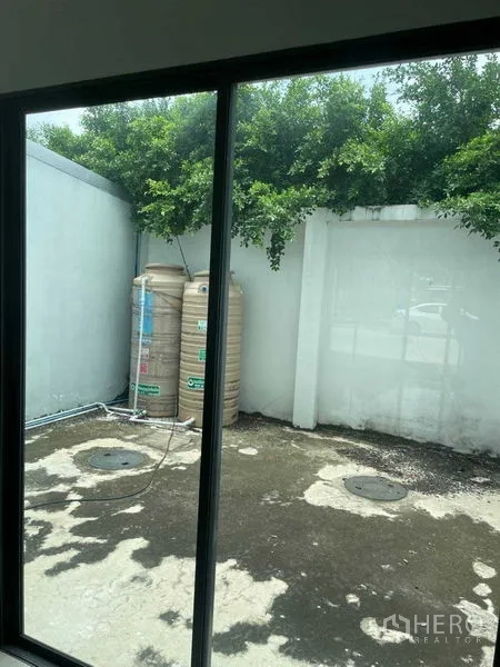 Townhouse for sale in Bueng Kum, Bangkok - Small rear patio with water storage tanks and a high privacy wall.