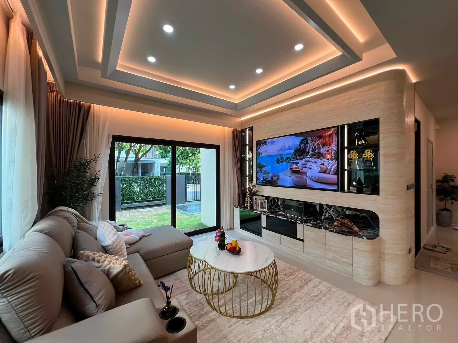Detached House for rent in Bang Phli, Samut Prakan - Living area with sectional sofa, feature wall, and sliding doors to lawn.