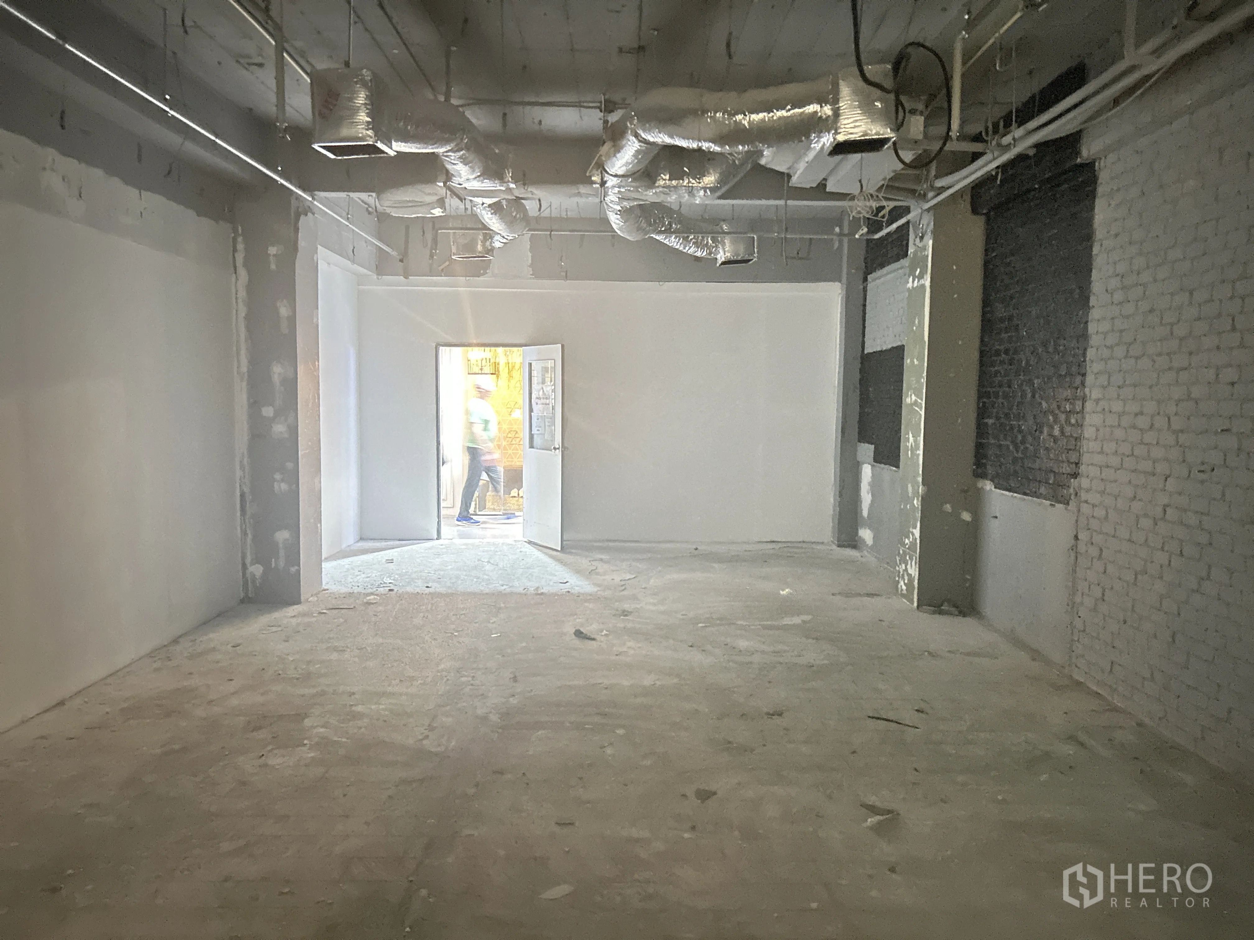 Retail Space for rent in Pathum Wan, Bangkok - Shell retail room with concrete floor, ductwork, and doorway to corridor.