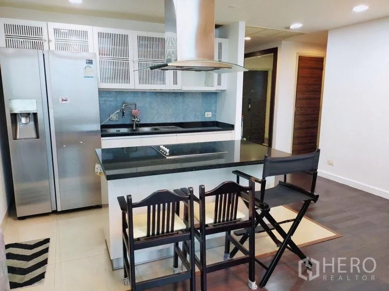 公寓 出租在Khlong San, Bangkok - 现代厨房，岛台电磁炉、不锈钢冰箱、吧台座椅与抽油烟机。