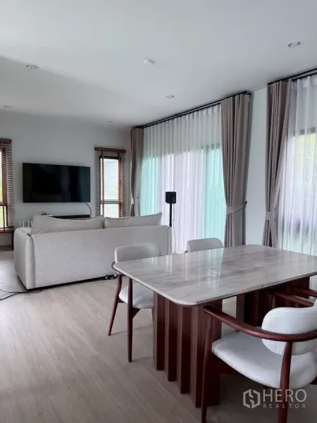 บ้าน ให้เช่าในLat Krabang, Bangkok - พื้นที่นั่งเล่น‑รับประทานอาหารแบบโอเพ่น พร้อมโต๊ะหินอ่อนและหน้าต่างสูงจรดเพดาน