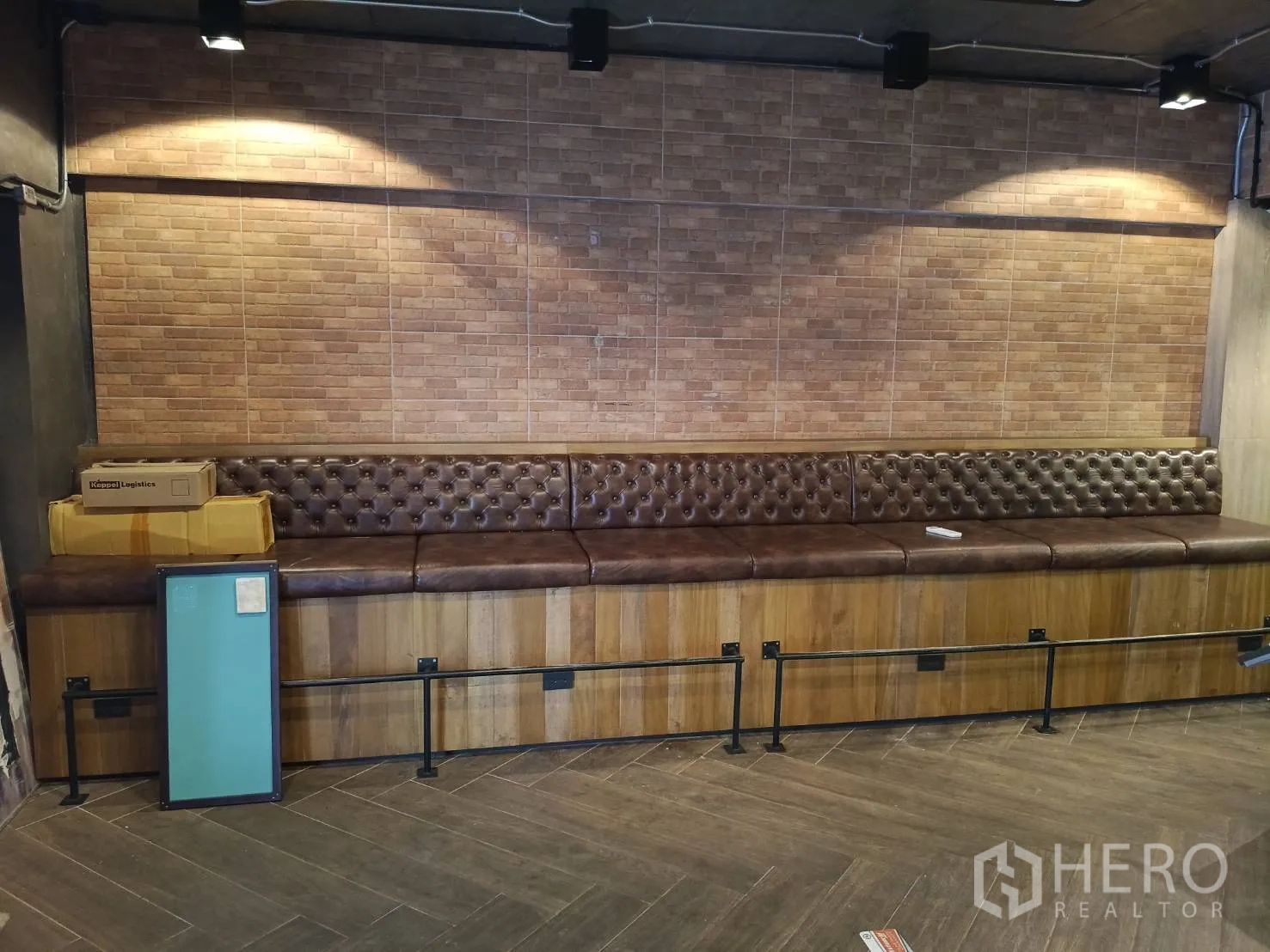 Retail Space for rent - Long tufted leather banquette against a brick accent wall under spotlights.