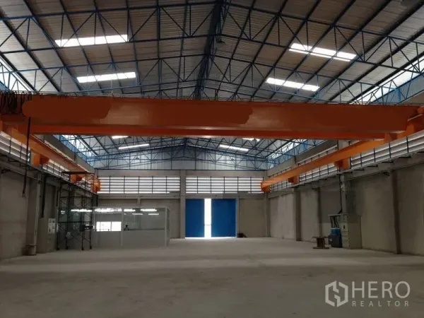 คลังสินค้า ให้เช่าในMueang Samut Prakan, Samut Prakan - มุมมองกึ่งกลางโกดัง แสดงคานรางเครนคู่และประตูทางเข้าขนาดใหญ่สีฟ้า