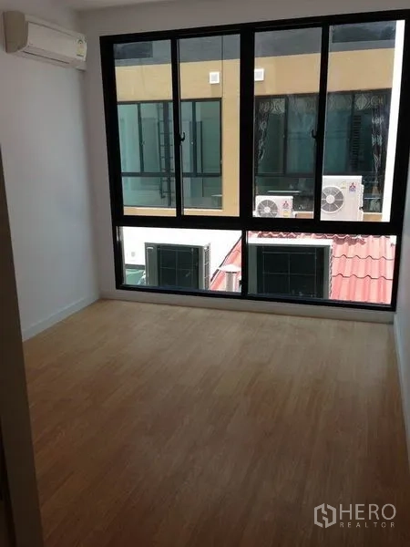 Townhouse for rent in Yan Nawa, Bangkok - Bedroom with full-height windows and wood laminate flooring.