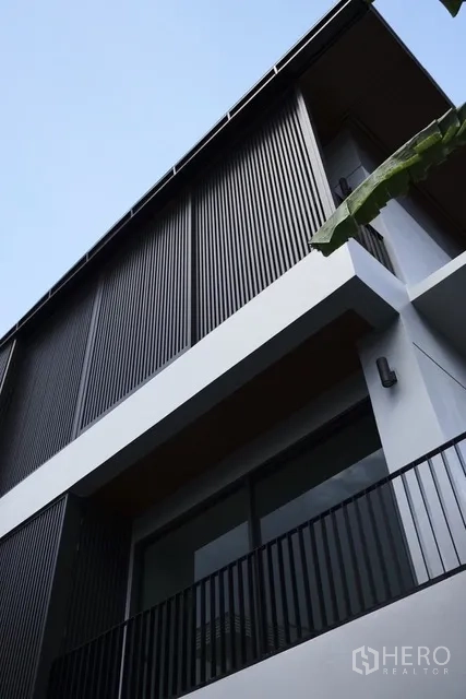Detached House for rent in Watthana, Bangkok - Close-up of facade with vertical slat screens and a balcony railing.