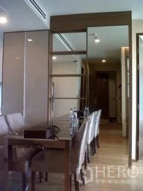 Condominium for rent or sale in Ratchathewi, Bangkok - Dining nook with sleek table, leather chairs and a mirrored partition beside the hallway.