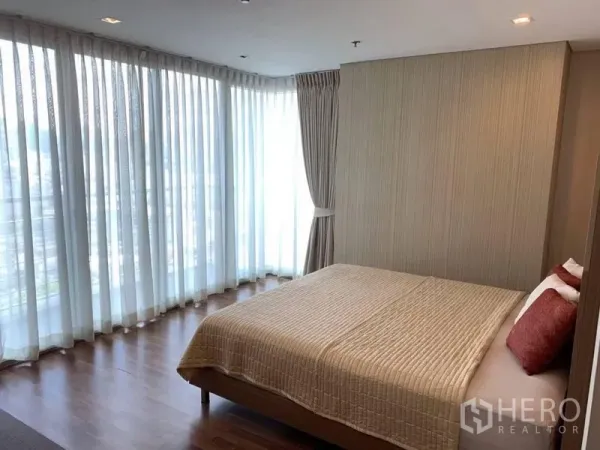 Condominium for rent in Watthana, Bangkok - Corner bedroom with wraparound floor-to-ceiling curtains and city views.