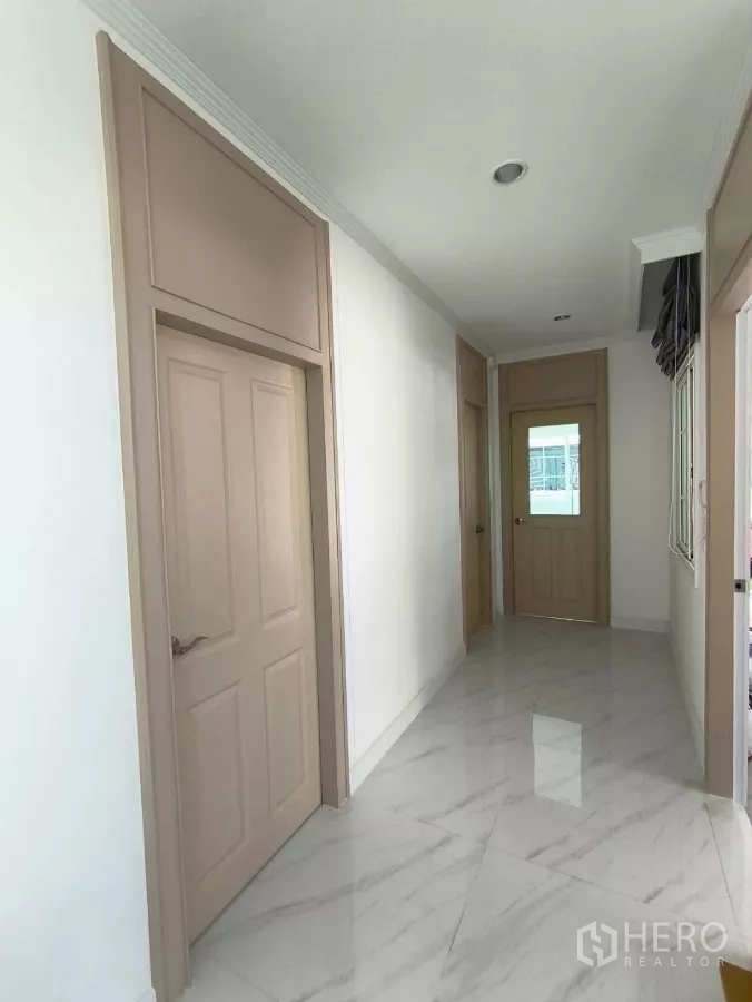 Detached House for rent in Bang Phli, Samut Prakan - Hallway with marble-effect tiles and soft beige doors leading to service and storage areas.