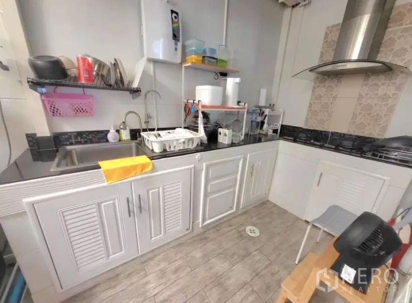 Townhouse for rent in Bang Phli, Samut Prakan - Separate Thai kitchen with white cabinets, gas hob and black stone countertop.
