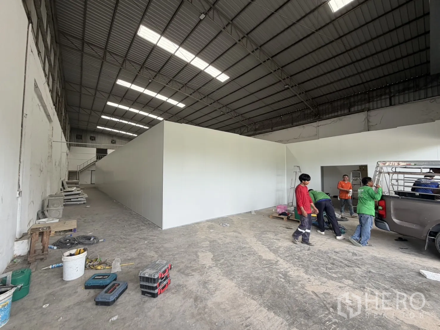 Warehouse for rent in Khlong Luang, Pathum Thani - Loading area inside the warehouse with open roller shutter, panel walls, equipment, and a pickup truck.