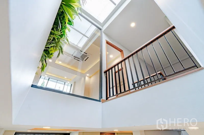 Townhouse for sale - Upward view of a skylit atrium with glass panels and black railing.