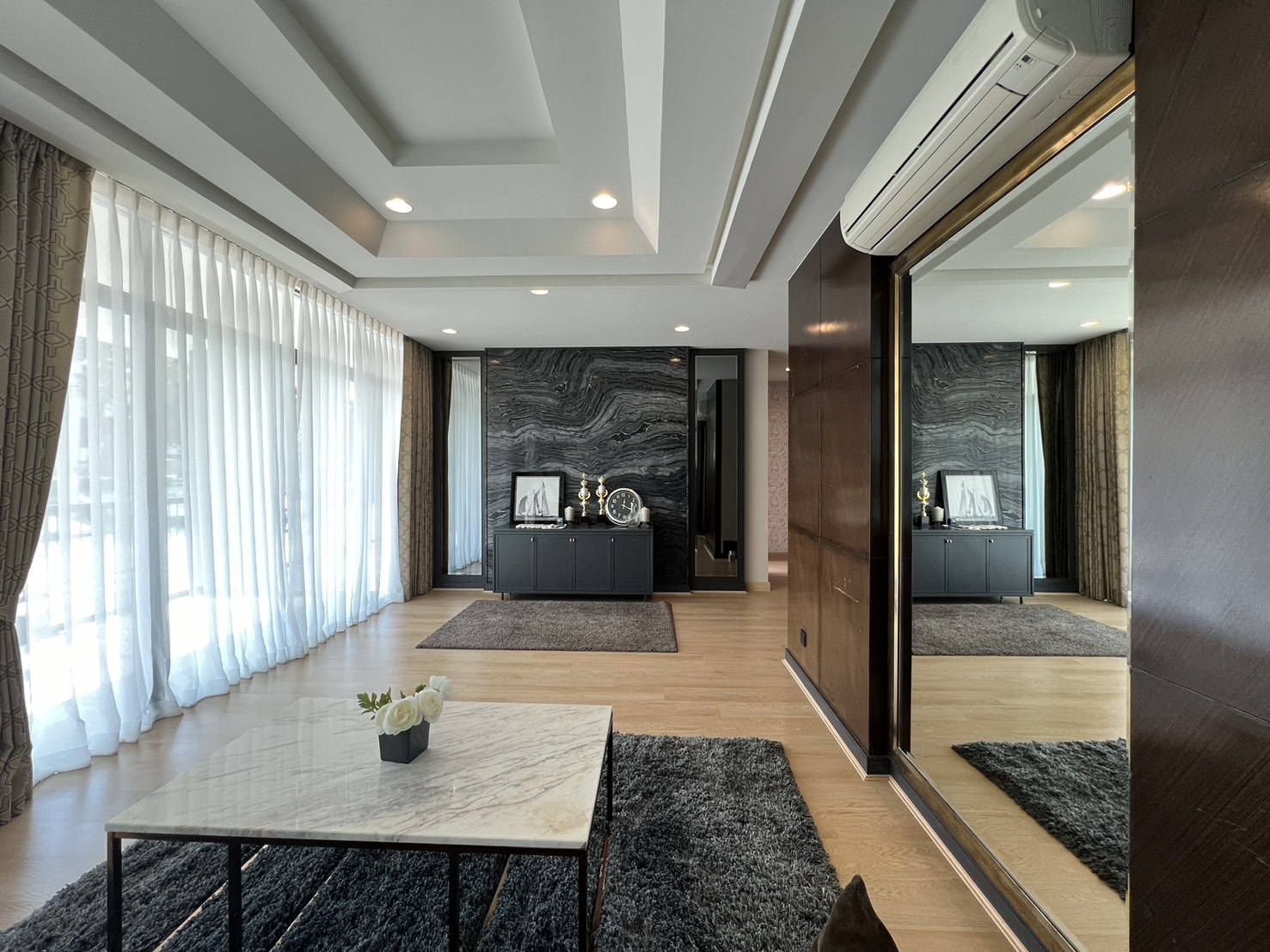 Detached House for rent in Bang Kapi, Bangkok - Spacious lounge with marble feature wall, mirrors and full-height windows.