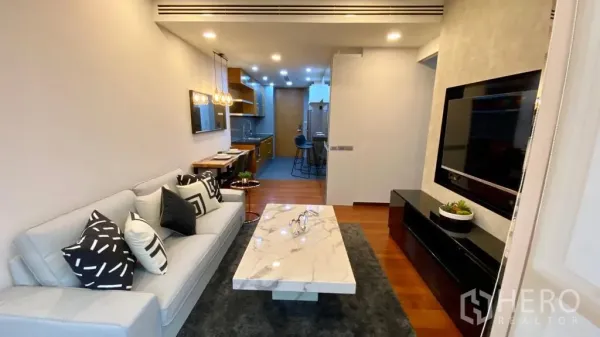 公寓 出售在Khlong Toei, Bangkok - 客厅面向电视墙，连接长廊式厨房，木地板。