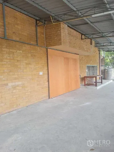 คลังสินค้า ให้เช่าในBang Yai, Nonthaburi - พื้นที่ภายนอกมีหลังคา ผนังอิฐ พร้อมประตูบานเลื่อนไม้และพื้นคอนกรีต
