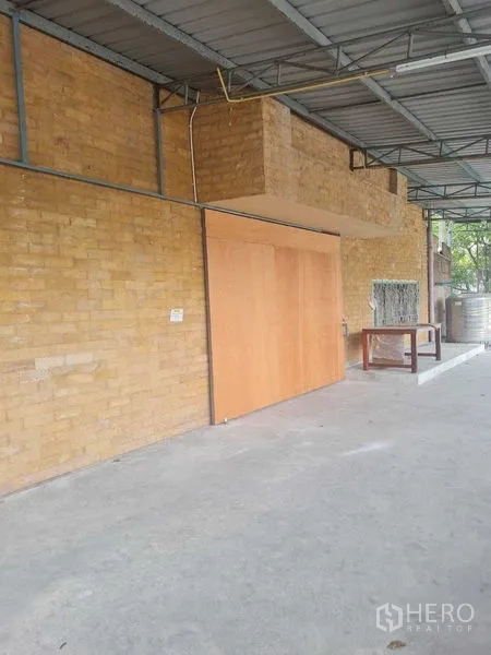คลังสินค้า ให้เช่าในBang Yai, Nonthaburi - พื้นที่ภายนอกมีหลังคา ผนังอิฐ พร้อมประตูบานเลื่อนไม้และพื้นคอนกรีต